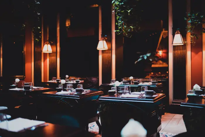 Warm, dimly lit restaurant dining room with pendant lights